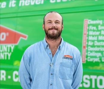 Picture of male SERVPRO employee wearing a denim button up in front of a SERVPRO van.